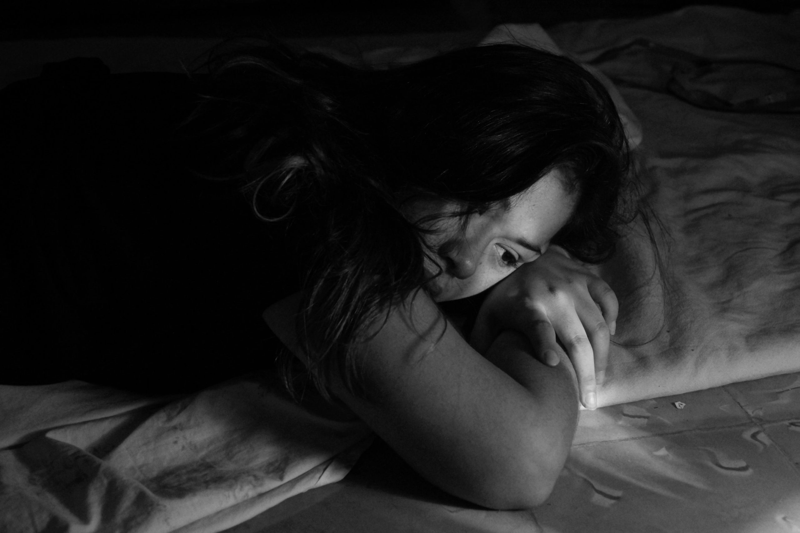 a woman lies in bed with her head resting on her arms as she looks out into the distant