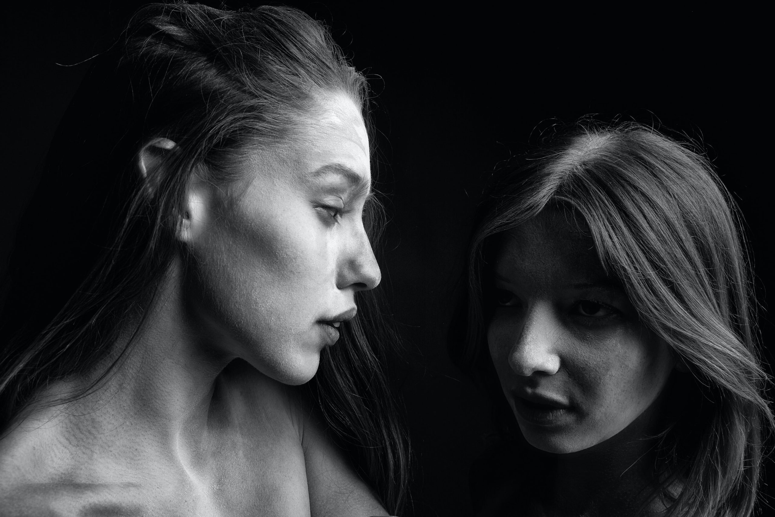 two women looking at each other, shadows on their faces